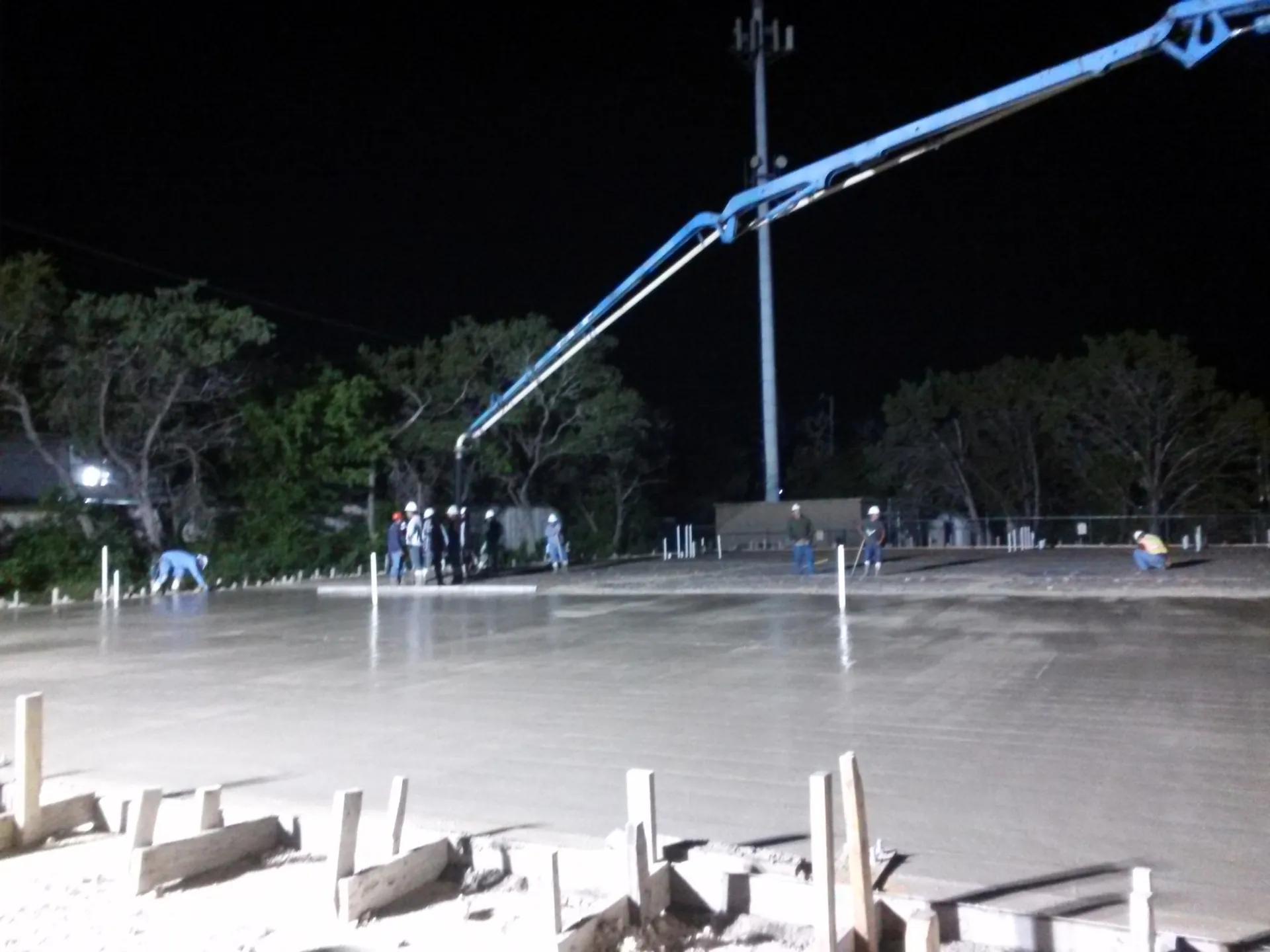 Concrete boom pump placing a commercial slab at night