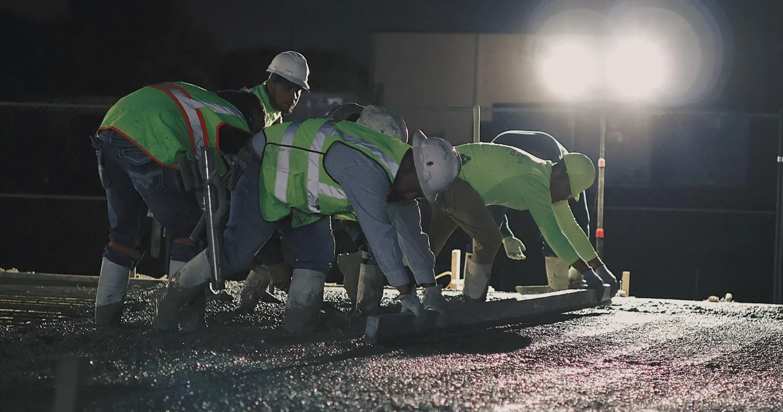 Esteban's Concrete crew screeding a slab under lights at night